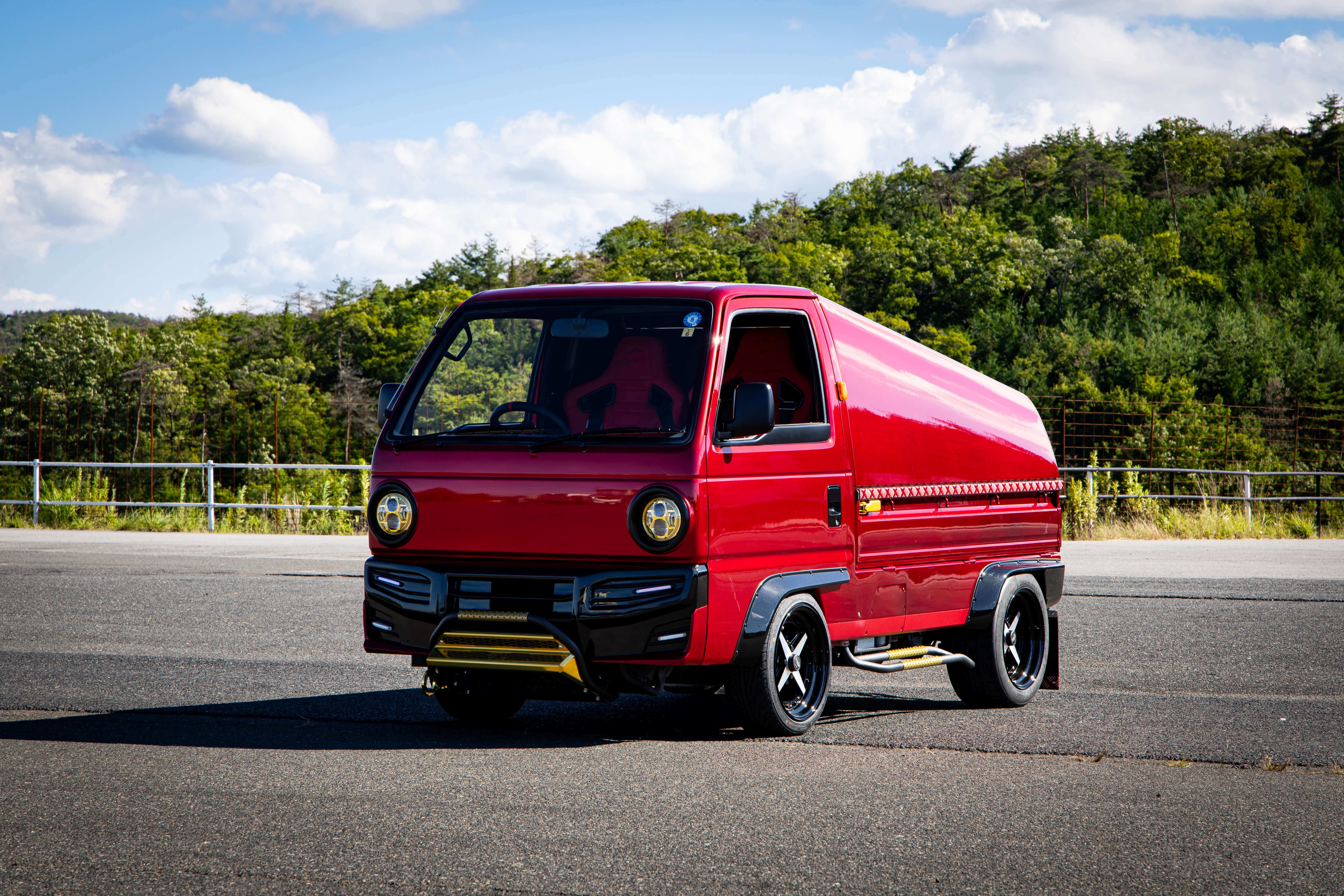 Custom red Honda Acty Grasshopper camper featuring unique retro styling, upgraded wheels, and aerodynamic camper shell, ready for adventure.