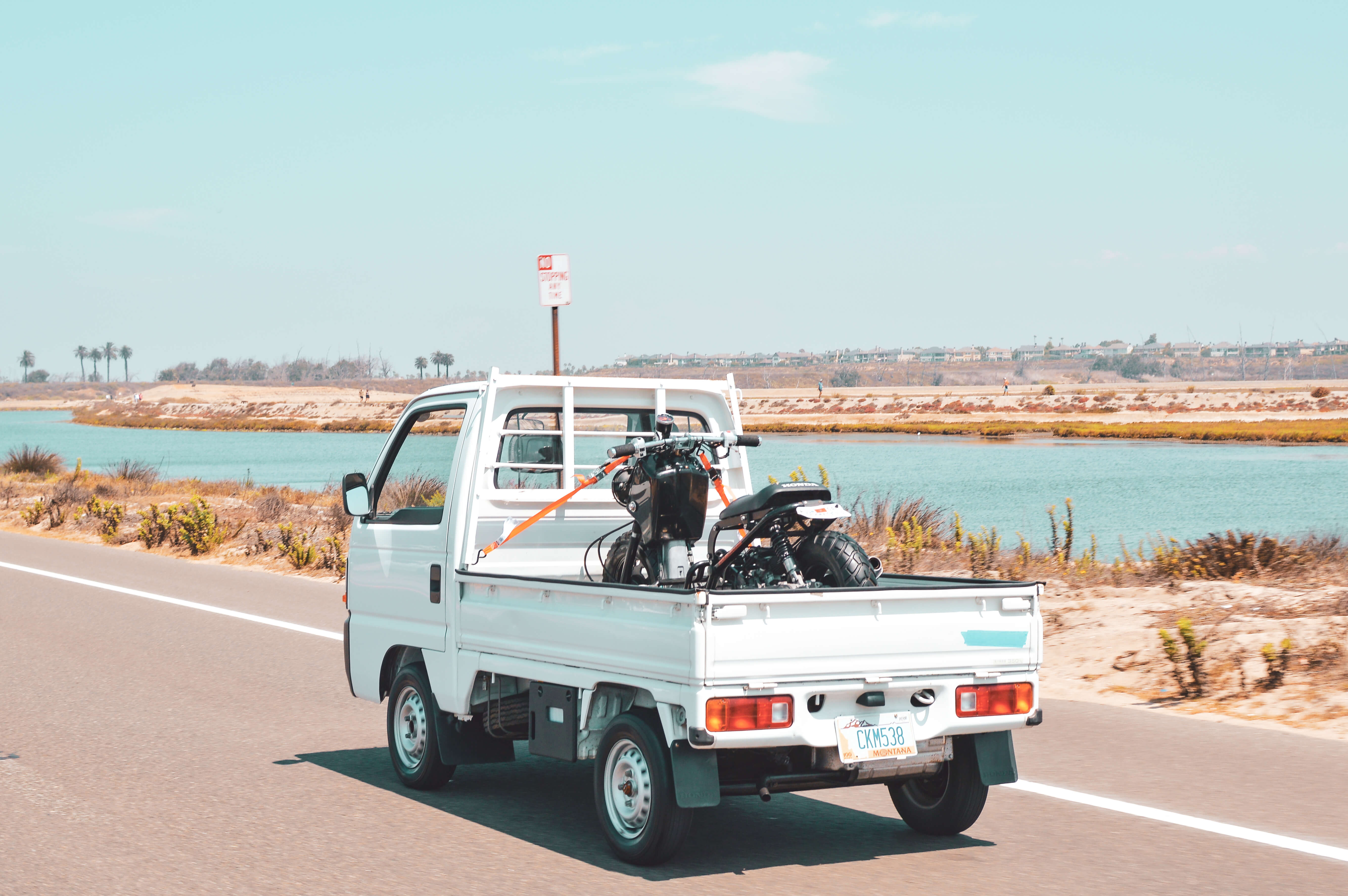 White honda acty truck transporting a honda ruckus on highway in California.