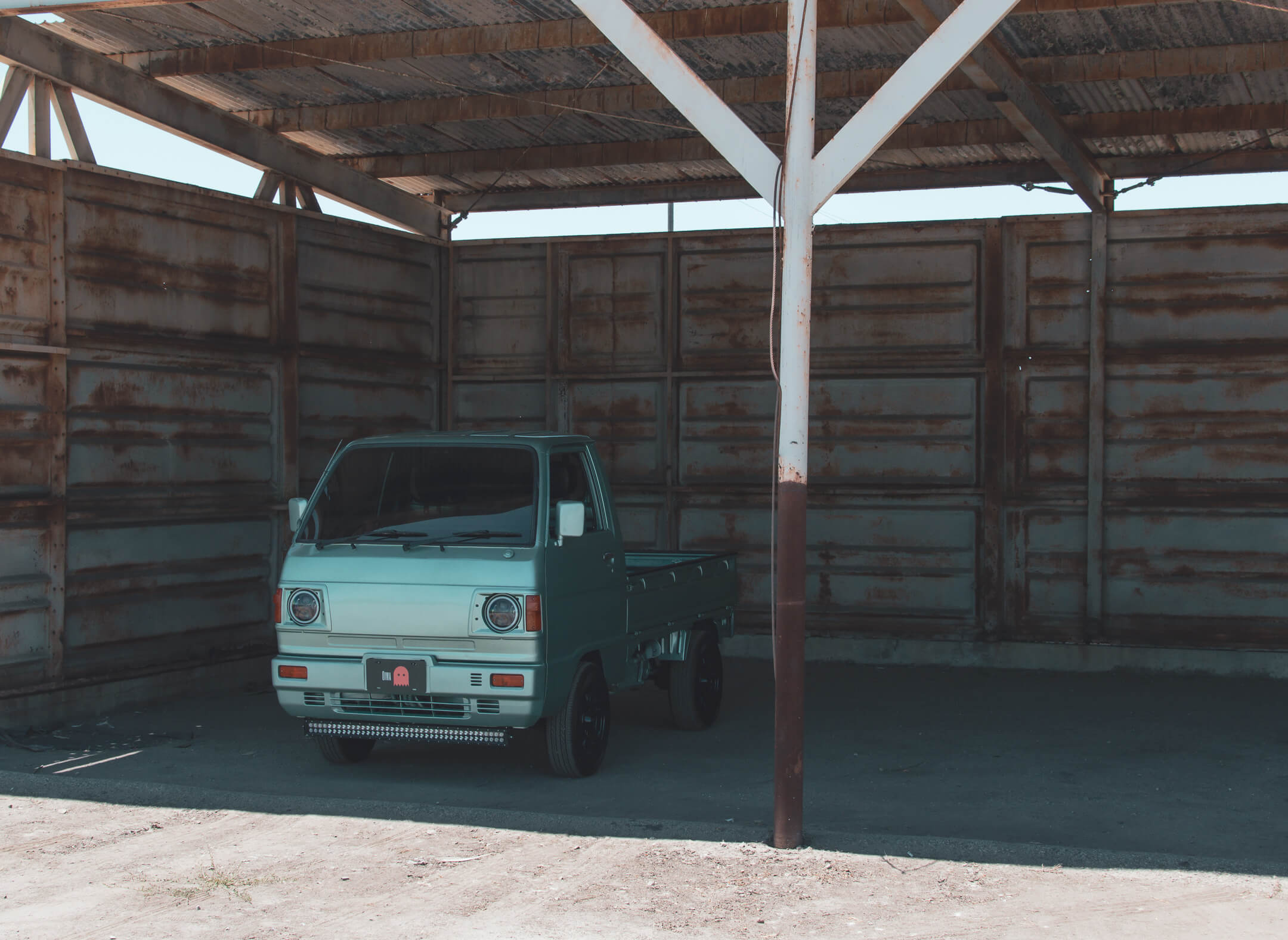 Green Kei Truck Parked Inside a Rustic Wooden Shelter in Montana