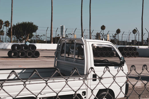 White Kei Truck Parked Near a Race Track with Palm Trees in the Background