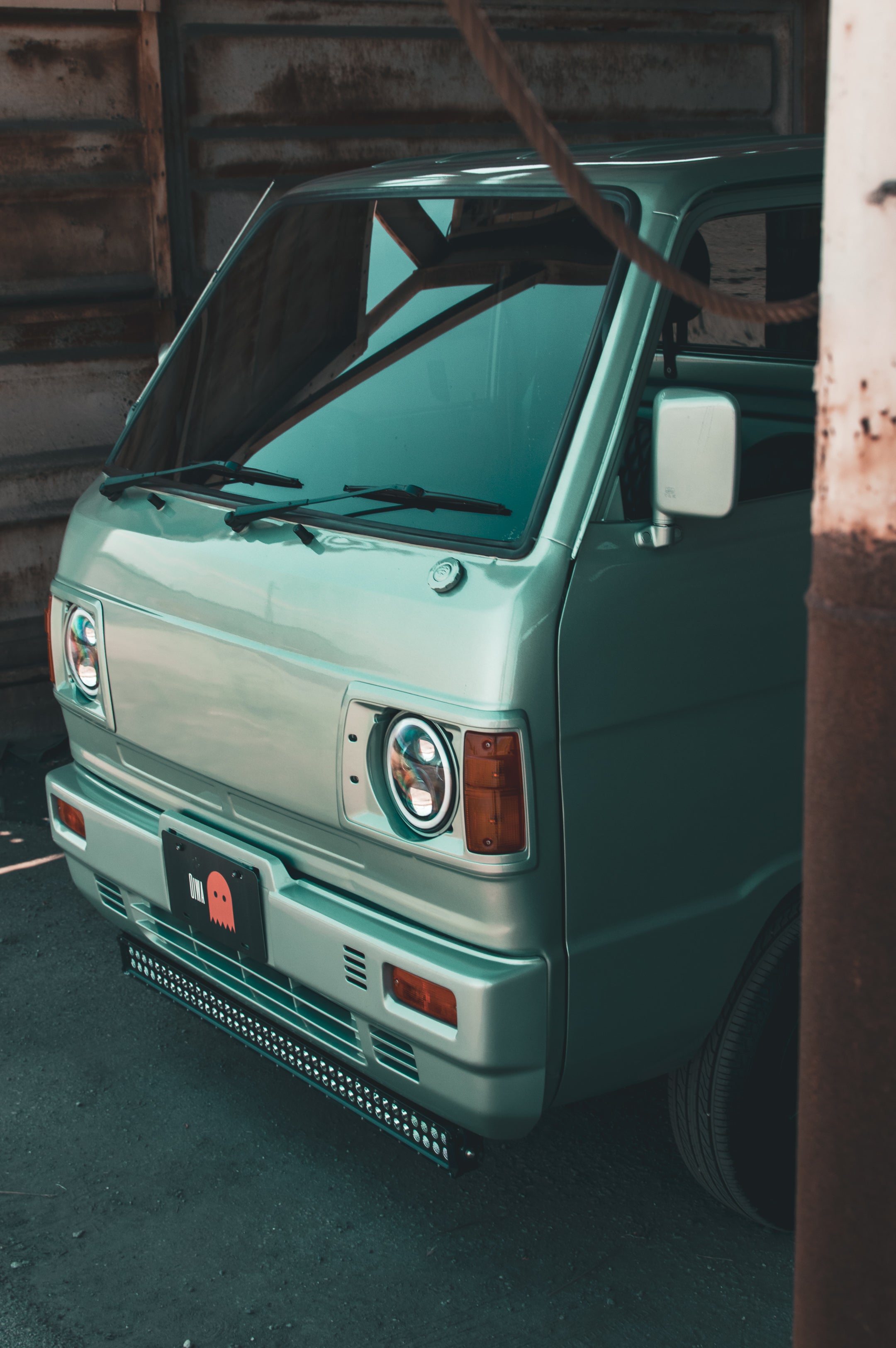 Subaru Sambar Dias kei van driving on a Japanese street, showcasing its compact and practical design.