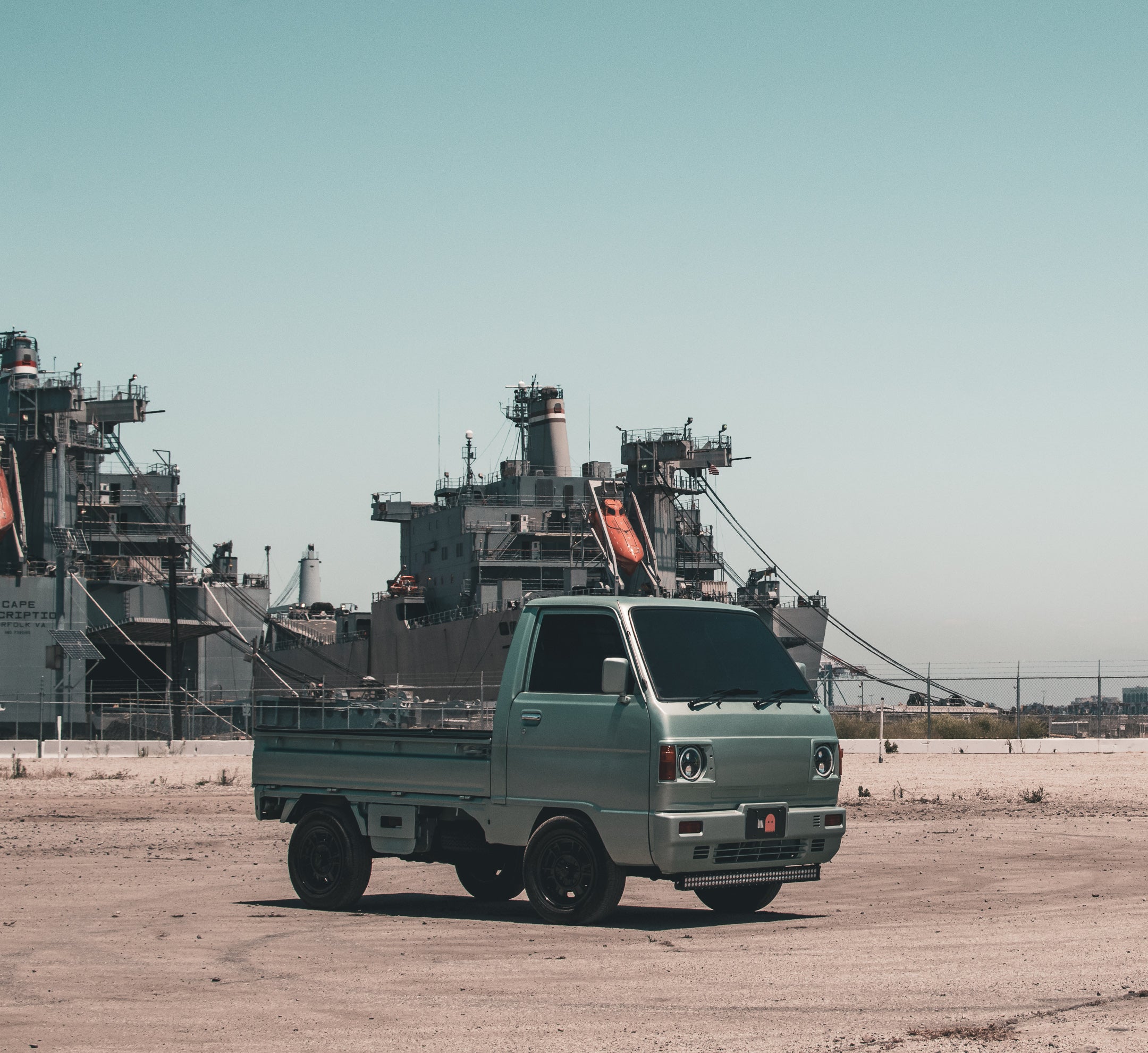 Subaru Sambar truck, a compact vehicle symbolizing Japanese innovation and resilience, parked in a scenic location, showcasing its unique design.