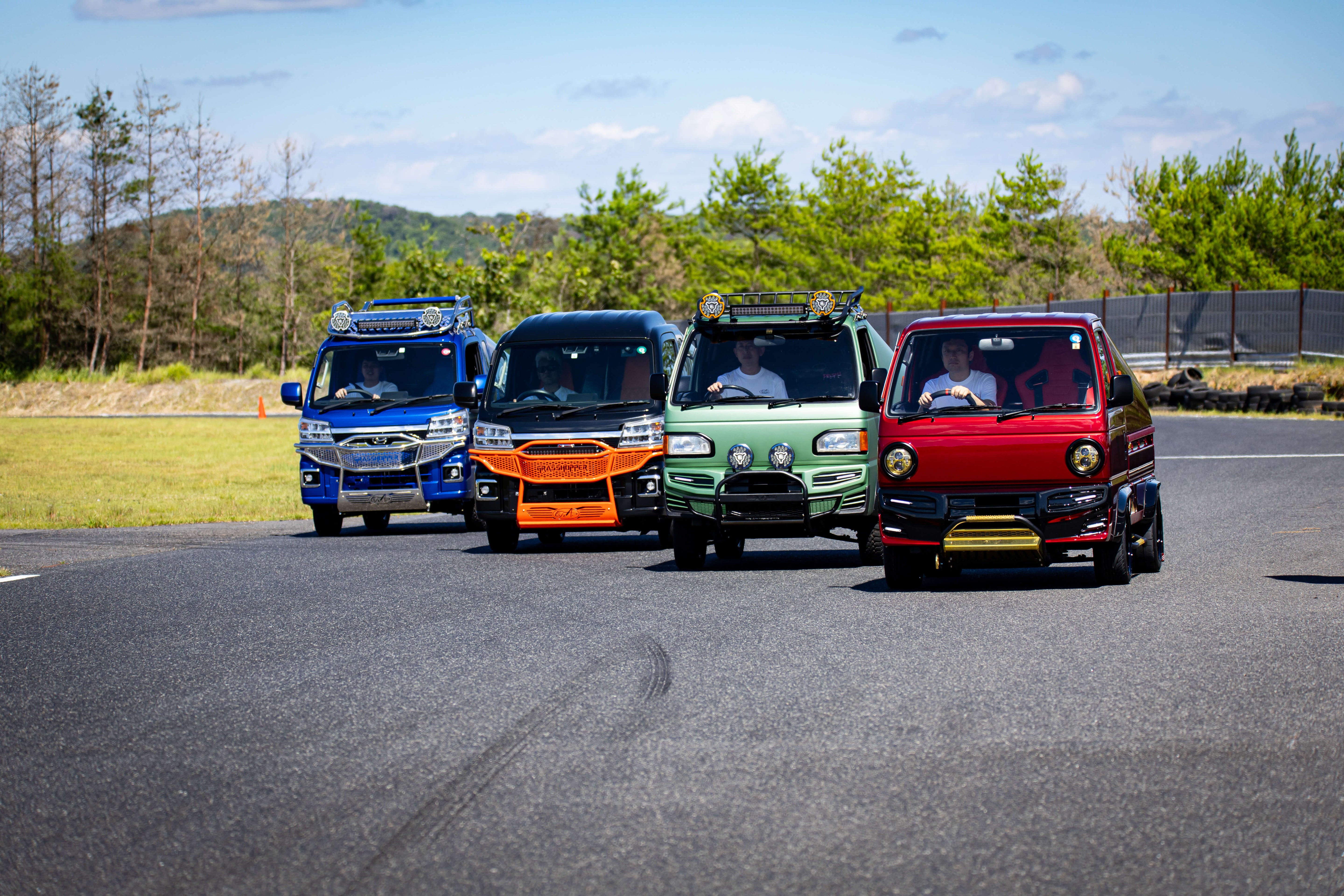 Colorful kei trucks driving on a road in Texas, showcasing compact design and utility.