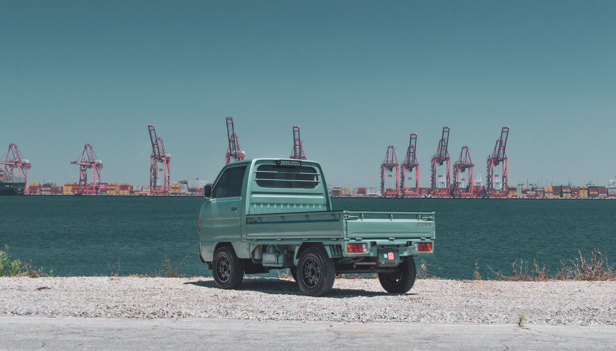 Kei truck navigating urban streets, showcasing its compact size and versatility in urban mobility.