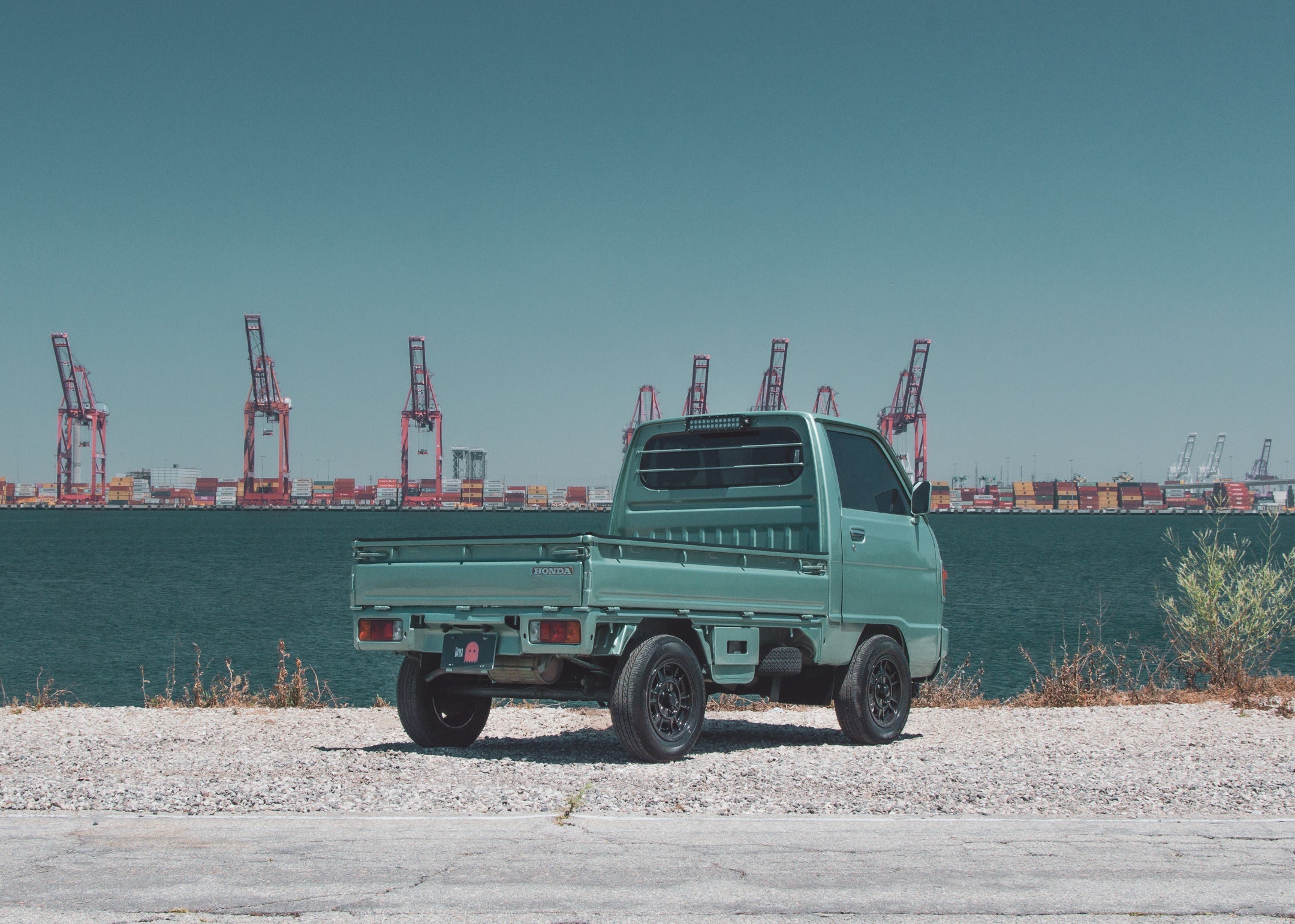 Suzuki Carry 4WD mini truck on a scenic road highlighting its compact and efficient design.