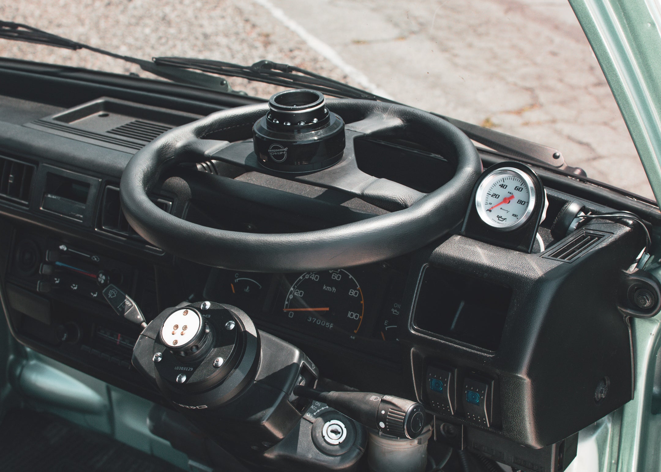 Interior of a hayabusa swapped kei truck with focus on dashboard and steering wheel, showcasing performance modifications and controls.