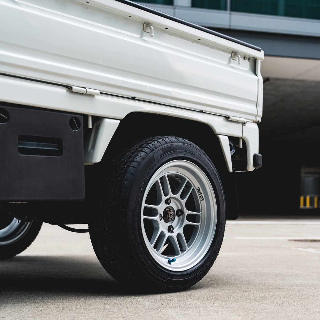 Close-up of silver aftermarket alloy wheels fitted perfectly to a white Honda Acty kei truck, demonstrating optimal fitment and style upgrade.