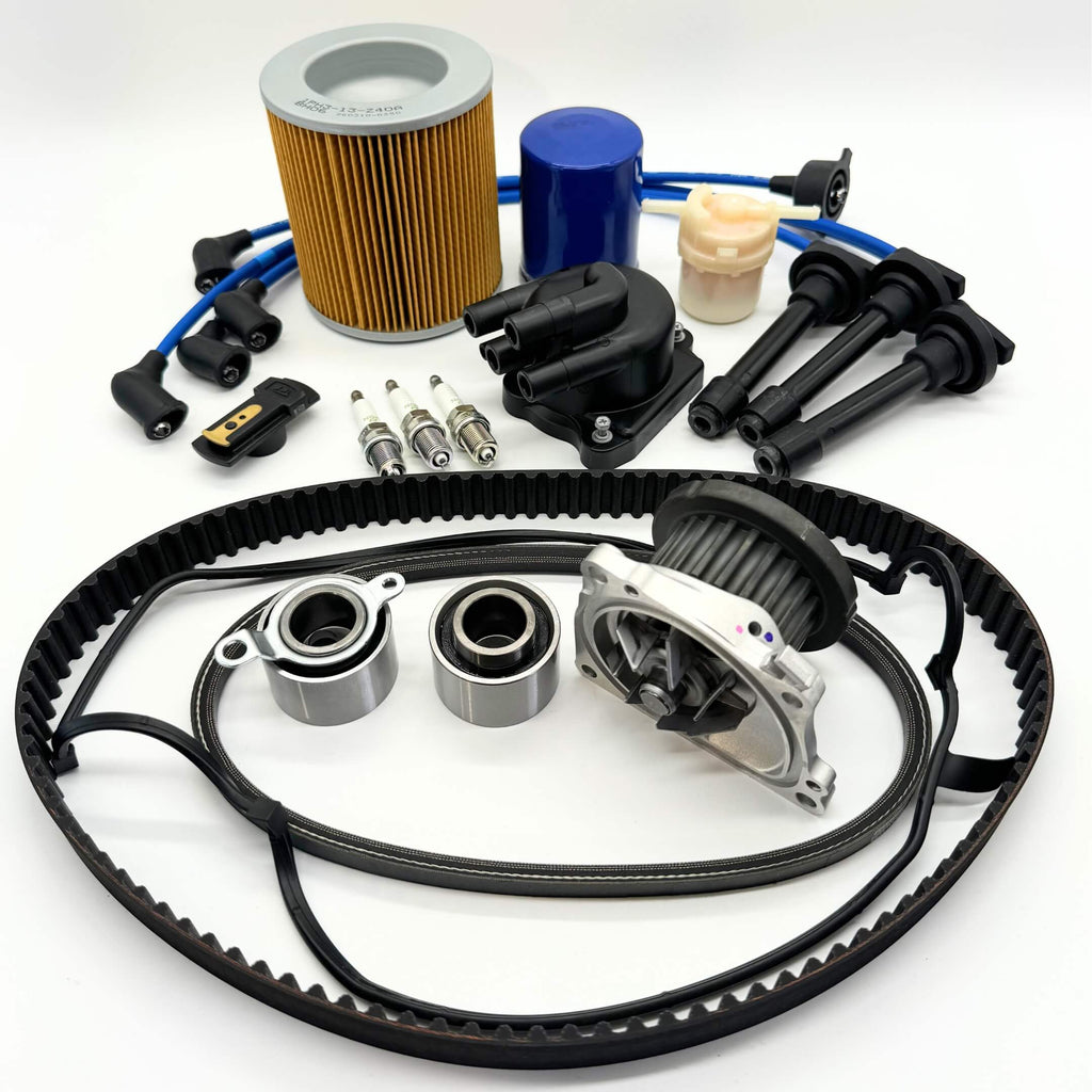 16-piece Mega Timing Belt and Tune-Up Kit for Honda Acty HA3/HA4 1990-1999, comprising an air filter, fuel filter, oil filter, distributor cap and rotor, spark plugs with wires, timing and alternator belt set, and head cover gasket, presented neatly on a white background, exclusively available with free shipping from Oiwa Garage.