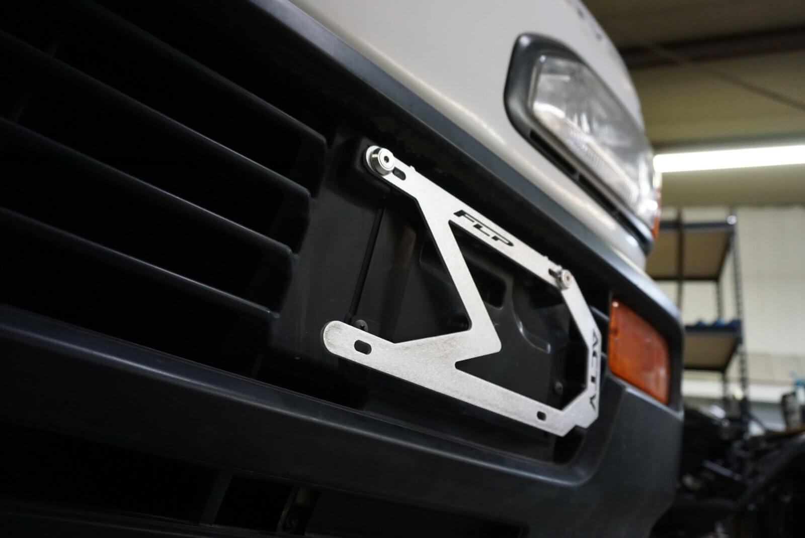 Easy-install USDM license plate adapter mounted on Honda Acty grille, showcasing the elegant integration and durability of the provided mounting hardware.