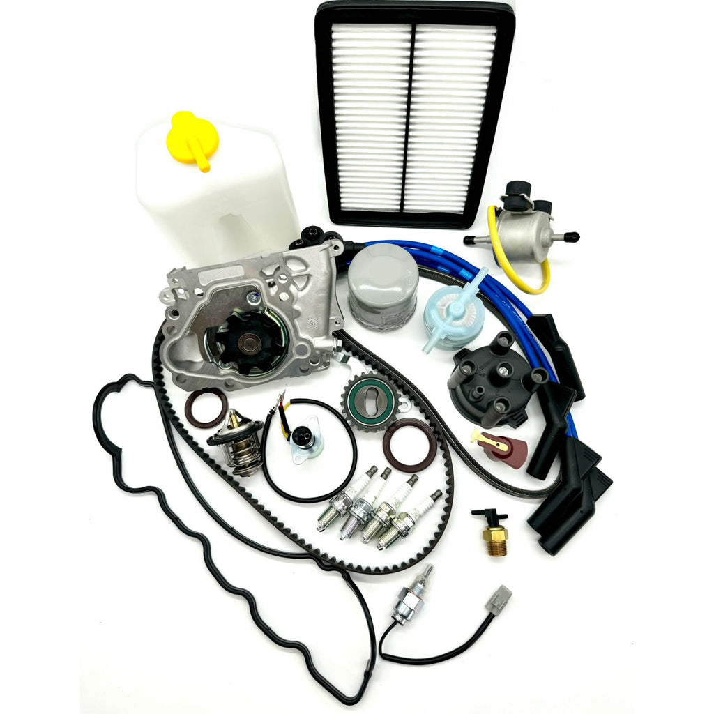 Subaru Sambar KS3 KS4 1990-1998 full 26-piece timing belt maintenance kit with essential engine parts including timing belt, tensioner, seals, water pump, alternator belt, thermostat, gaskets, filters, spark plugs, ignition system components, coolant tank, carburetor valves, fuel pump, and 2-prong thermo valve assembly.