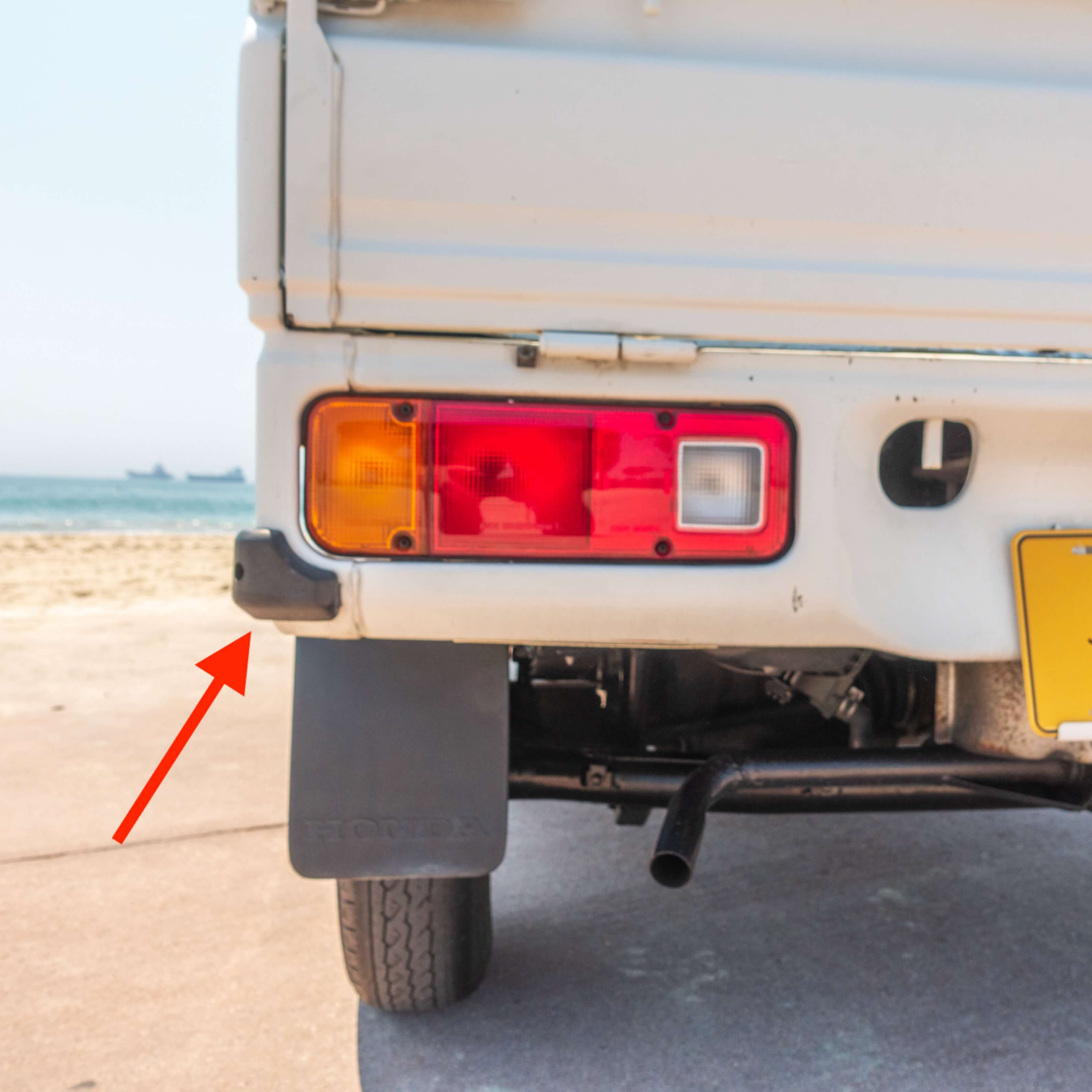 Installation point for Rubber Gate Stopper on a white Honda Acty Truck, model years 1990-1999, highlighting the rear gate area with an arrow indicating the exact mounting position.