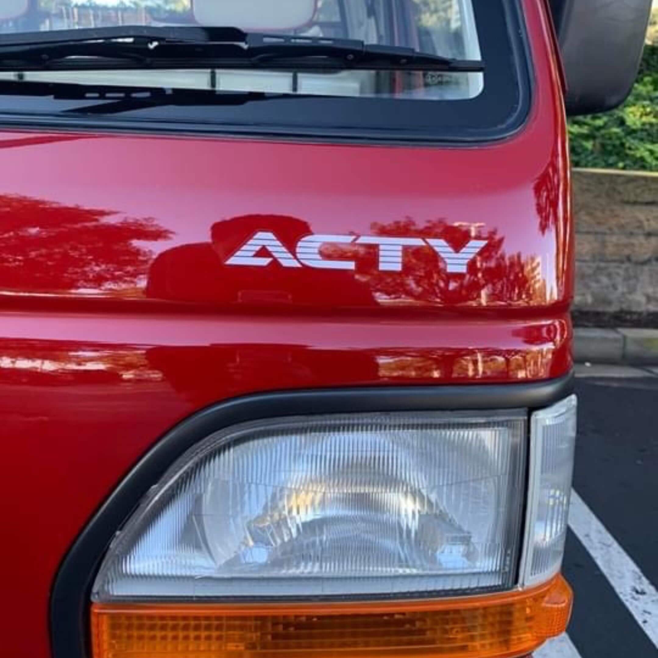 Close-up of red Honda Acty truck showcasing the bold ACTY logo on the hood, perfect for Honda enthusiasts looking to enhance their vehicle's aesthetic.