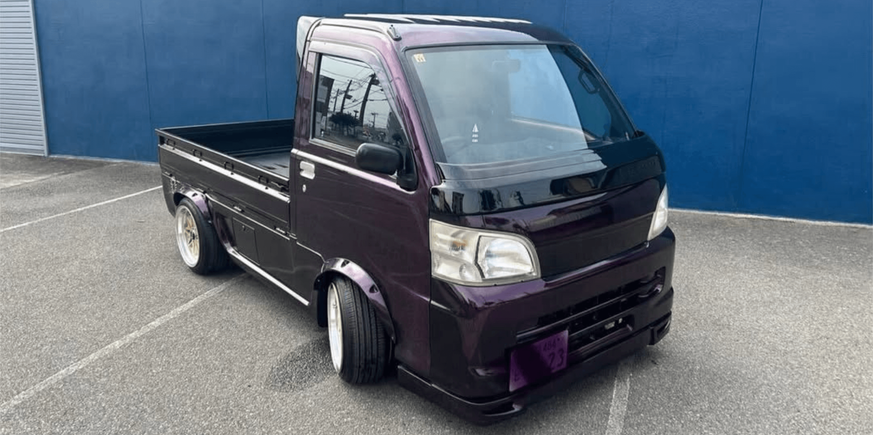 2001 Daihatsu Hijet S210P kei truck in deep metallic purple featuring custom lowered stance, flared fender arches, sleek body kit with front lip spoiler, and gold deep-dish alloy wheels – perfect for stylish mini truck enthusiasts.