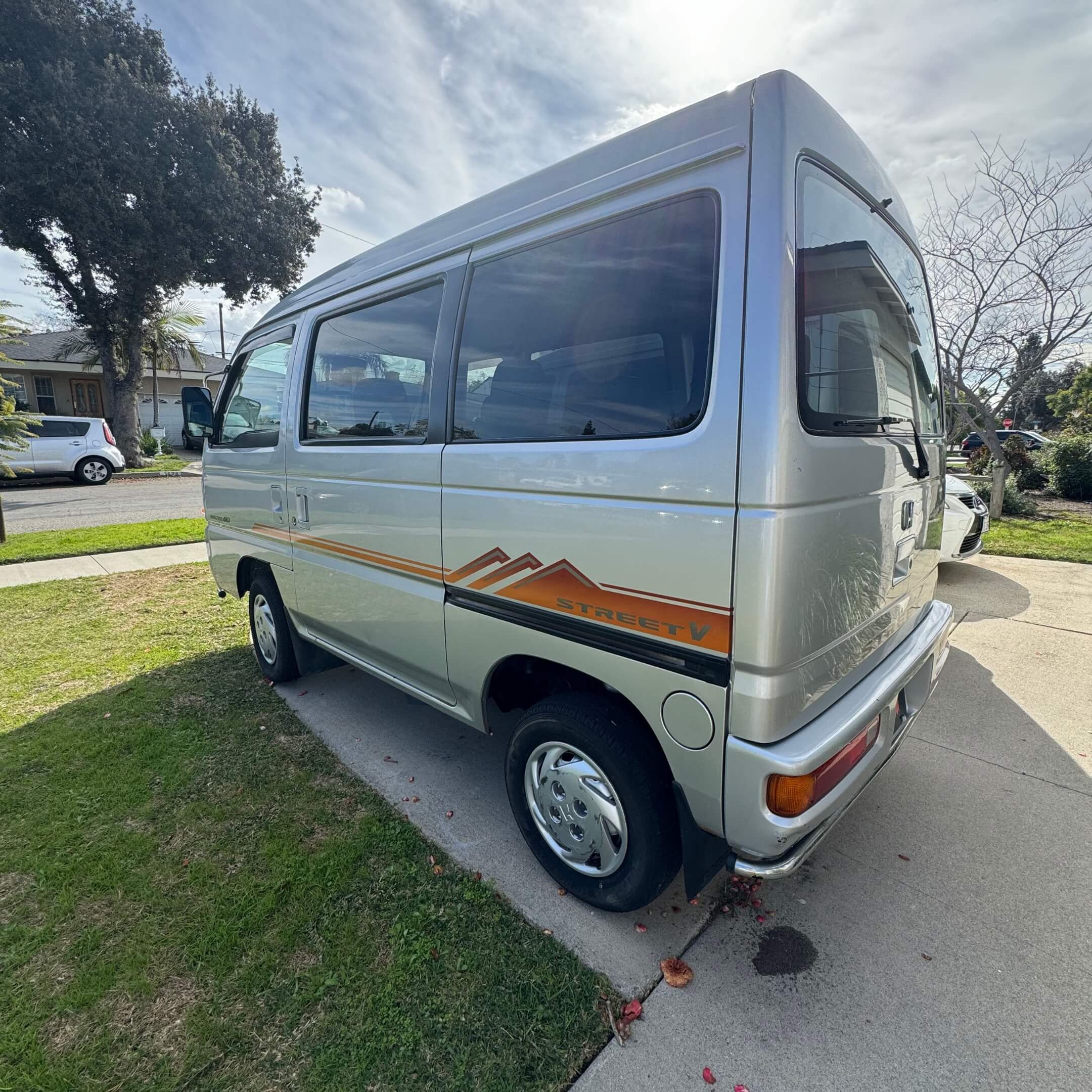 Angled side view of a Honda Street Van HH4 showcasing the orange and grey Street V side decal, highlighting the vintage aesthetic for Japanese kei vehicle collectors.