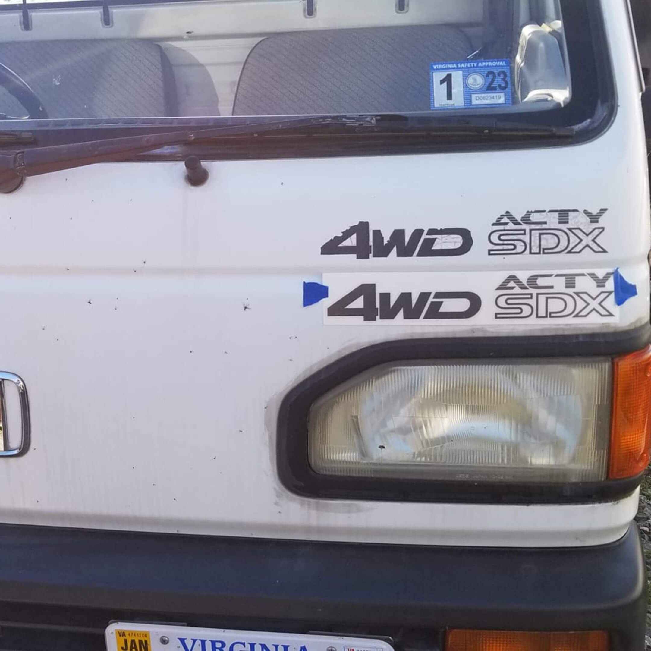 Side profile of a white Honda Acty truck featuring 4WD SDX decals, highlighting the truck's off-road capabilities and design.