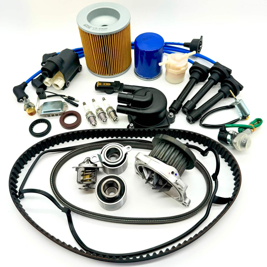 22-piece Mega Timing Belt and Tune-Up Kit for 1990-1999 Honda Acty HA3/HA4, including premium air filter, fuel filter, oil filter, distributor cap and rotor, high-performance spark plugs with wires, ignition control module, coil sensor, ignition assembly, complete engine gasket set, timing and alternator belts, and air thermal valve, all arranged on a white background, ready to ship free from Oiwa Garage.