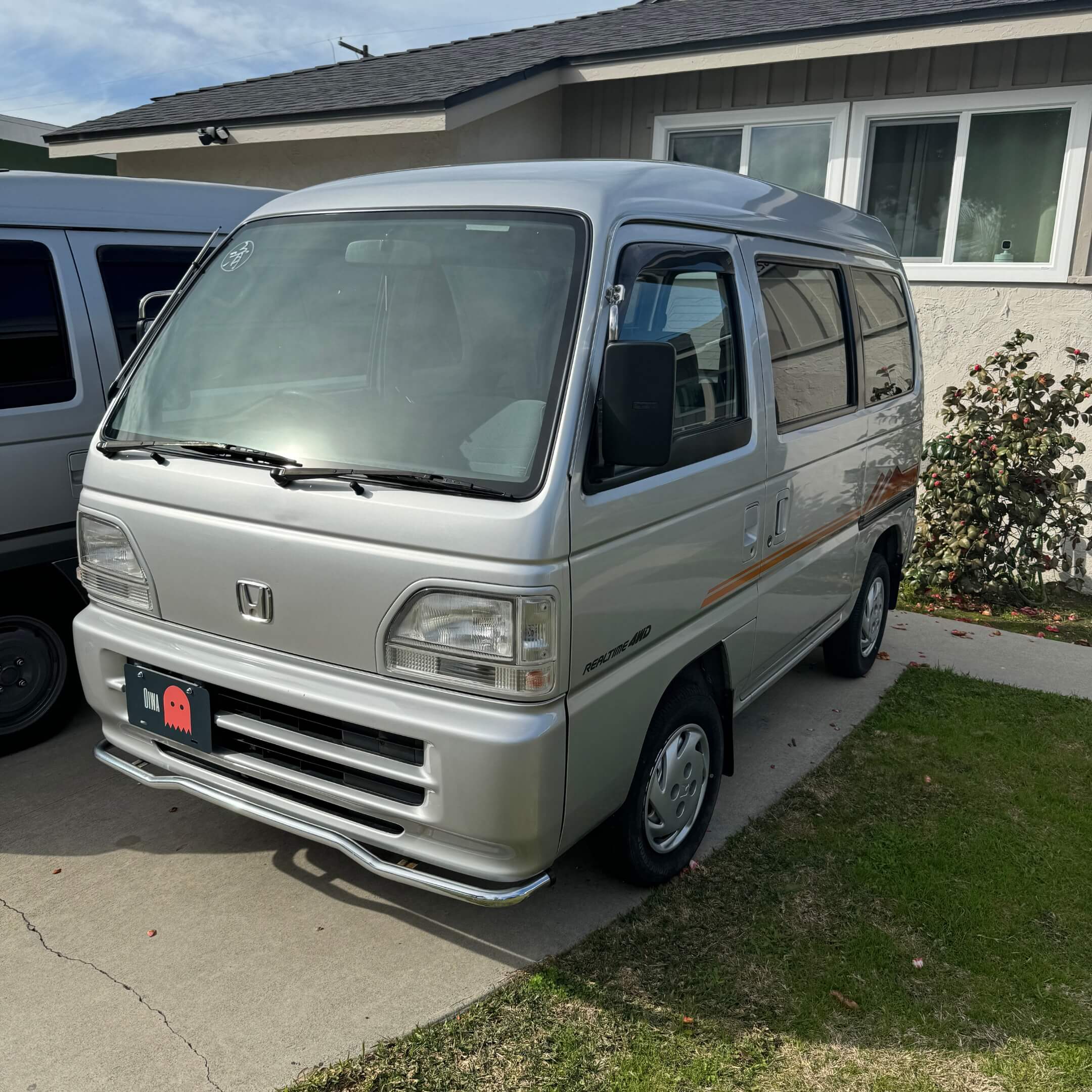 Front view of Honda Street Van HH3 model with orange Street V side decal, showcasing the classic 1990s compact design and Honda's emblem, ideal for Japanese kei vehicle enthusiasts.