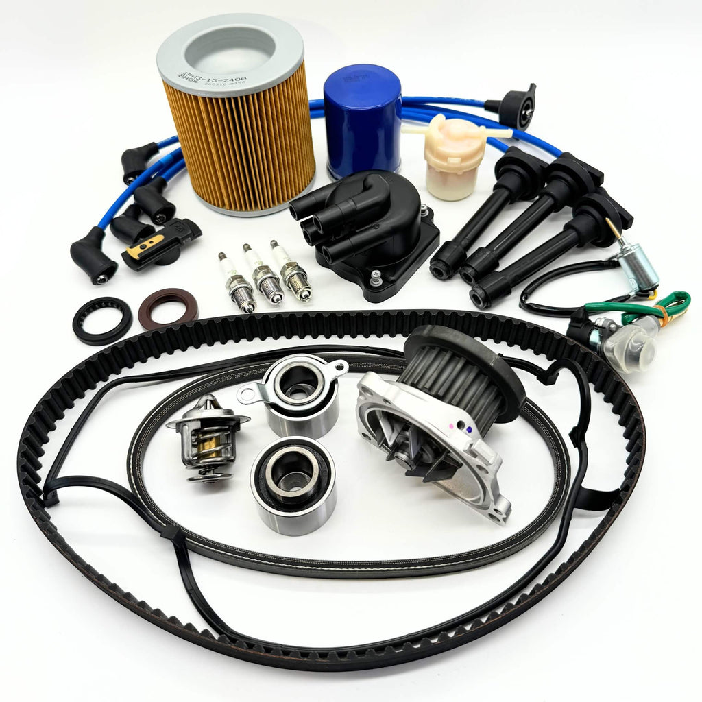 18-piece Mega Timing Belt and Tune-Up Kit for Honda Acty HA3/HA4 1990-1999, including high-quality air filter, fuel filter, oil filter, distributor cap and rotor, spark plugs and wires, premium timing and alternator belts, head cover gasket, and carb solenoids, neatly arranged on a white background with free shipping from Oiwa Garage.