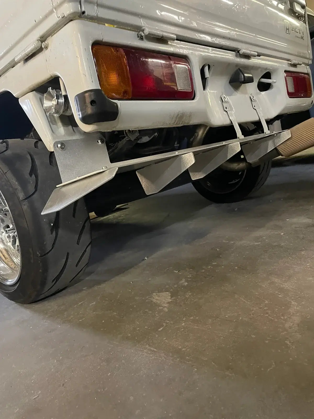Rear diffuser for Honda Acty Truck HA3, HA4 models (1990-1999), silver metal, angled view, installed under rear bumper