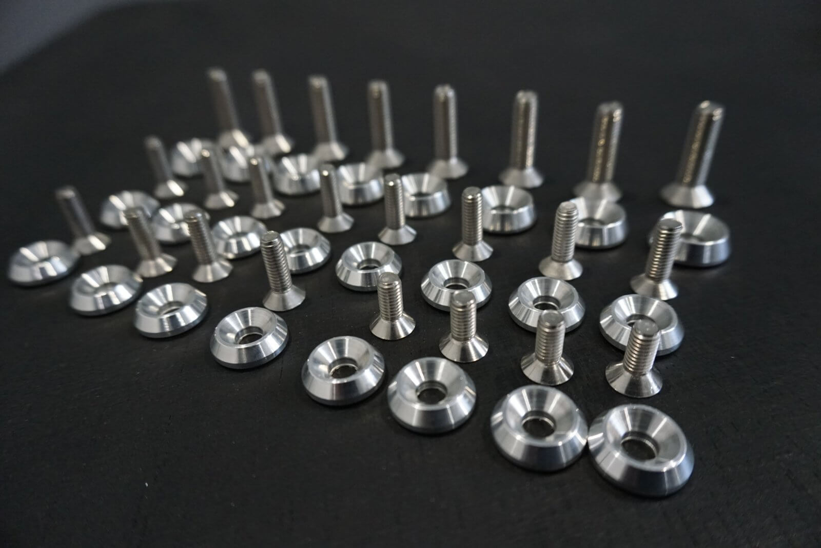 Stainless Bed Bolt Kit Upgrade for Honda Acty Truck, featuring various sizes of shiny bolts and washers on a dark surface