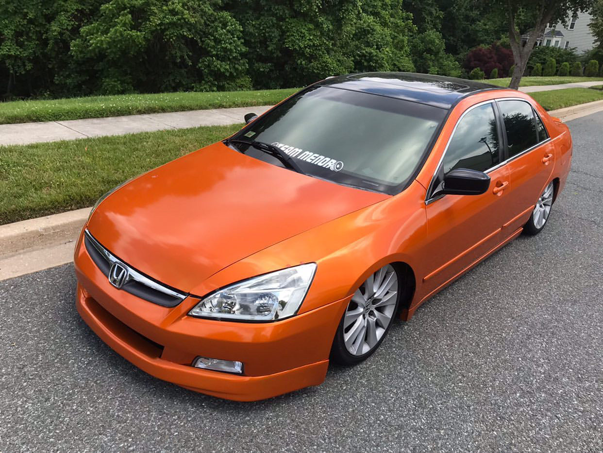 Orange Honda sedan with Nebula Black tint by Omnique, providing a unique reflective black look