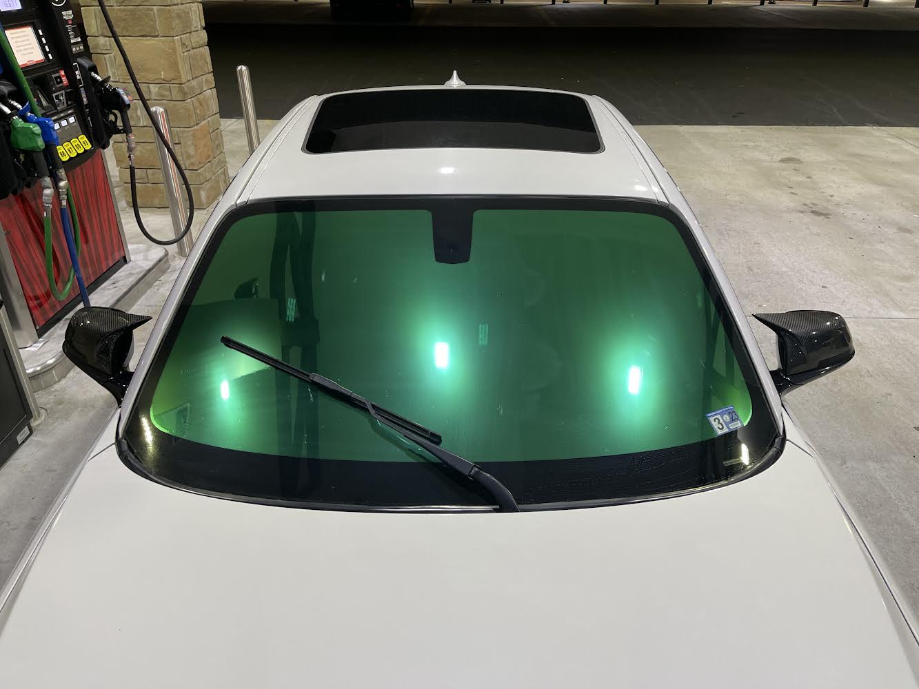 Close-Up of Omnique Peridot Green Tint on BMW Windshield: Reflective Peridot green one-way mirror tint applied to the windshield of a BMW.