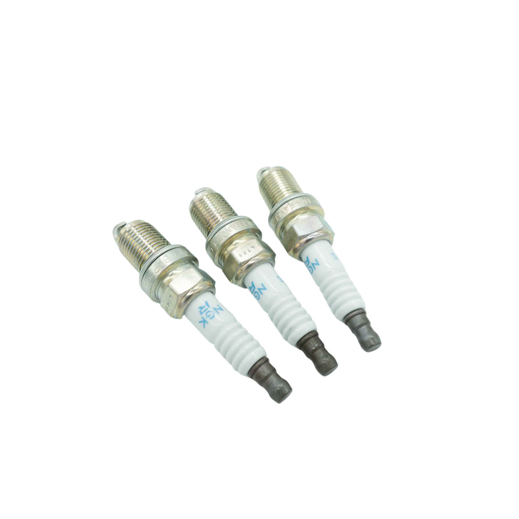 Set of three pristine spark plugs for Honda Acty HA3 HA4 series from 1990-1999, displayed at an angle to showcase brand markings and ceramic insulation, essential for engine maintenance