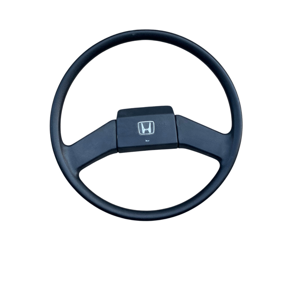 1990-1999 Honda Acty HA3, HA4, HH3, HH4 OEM black steering wheel with classic three-spoke design and Honda logo, showcasing a smooth finish for comfortable grip.